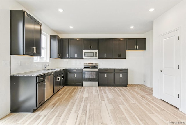 kitchen with sink, decorative backsplash, light hardwood / wood-style floors, light stone counters, and stainless steel appliances