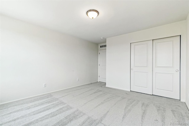 unfurnished bedroom featuring light colored carpet and a closet