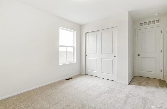 unfurnished bedroom featuring light carpet and a closet