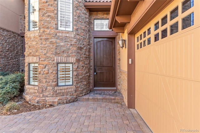 view of exterior entry featuring a garage and stone siding