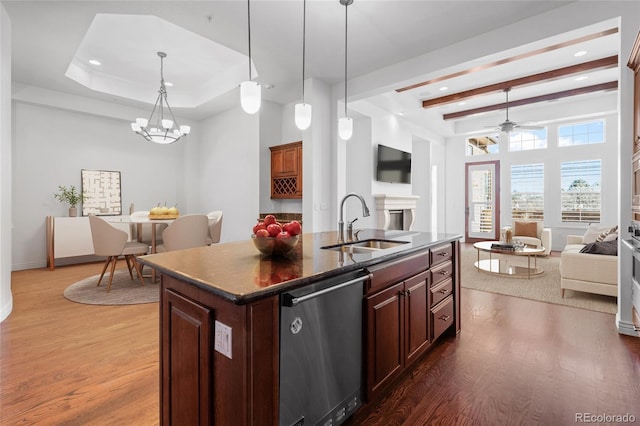 kitchen featuring a sink, open floor plan, dishwasher, an island with sink, and dark countertops