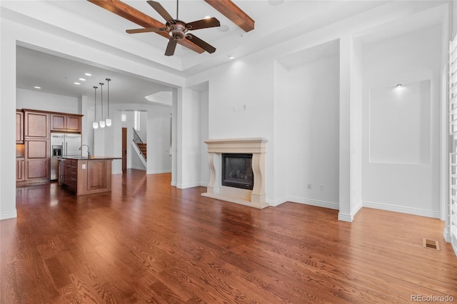 unfurnished living room featuring baseboards, visible vents, a glass covered fireplace, dark wood-type flooring, and stairs