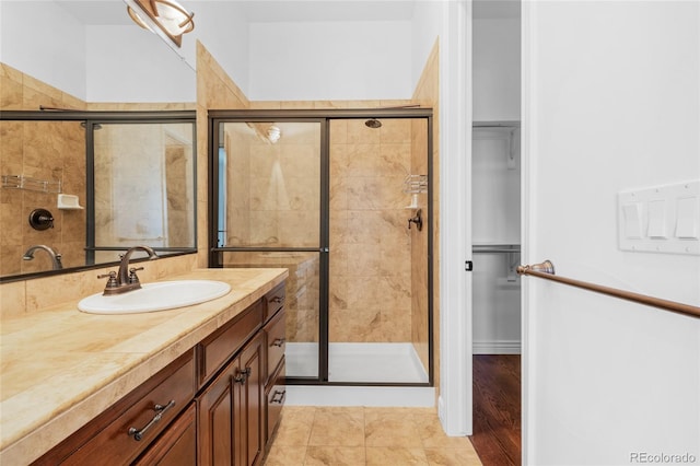 bathroom with tile patterned floors, a walk in closet, vanity, and a shower stall