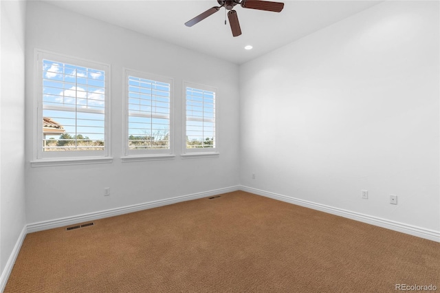 spare room featuring carpet, visible vents, ceiling fan, and baseboards