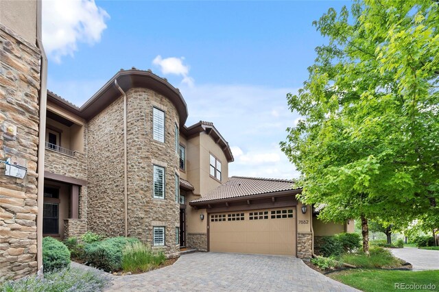 7882 Vallagio Ln, Englewood, CO 80112 - view of front of home with stone siding, stucco siding, a garage, decorative driveway, and a tiled roof