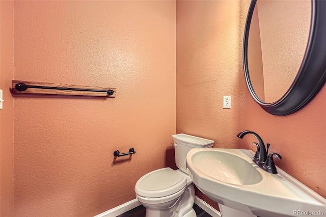 2761 W 106th Loop Unit C, Denver, CO 80234 - bathroom featuring toilet, a sink, a textured wall, and baseboards