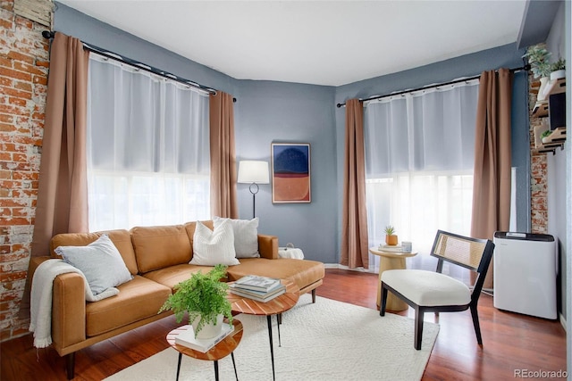 living room featuring brick wall and hardwood / wood-style flooring