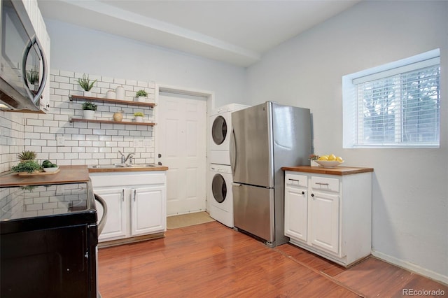 laundry room with stacked washer / dryer, sink, and light hardwood / wood-style flooring