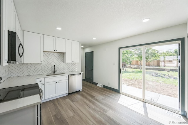 7810 Larkwood St, Commerce City, CO 80022 - kitchen featuring appliances with stainless steel finishes, decorative backsplash, light wood-style floors, white cabinetry, and light countertops