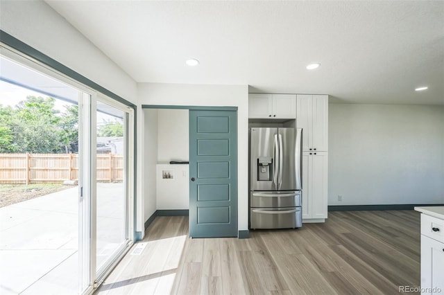 7810 Larkwood St, Commerce City, CO 80022 - kitchen with stainless steel refrigerator with ice dispenser, light wood finished floors, white cabinetry, recessed lighting, and light countertops