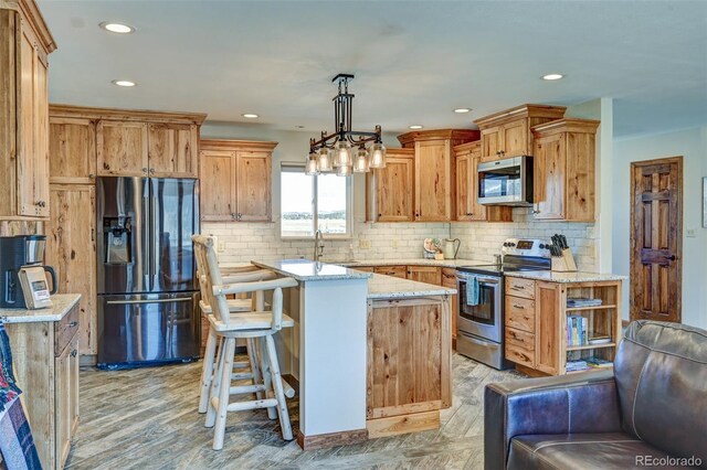 kitchen featuring light stone counters, a center island, stainless steel appliances, tasteful backsplash, and hanging light fixtures