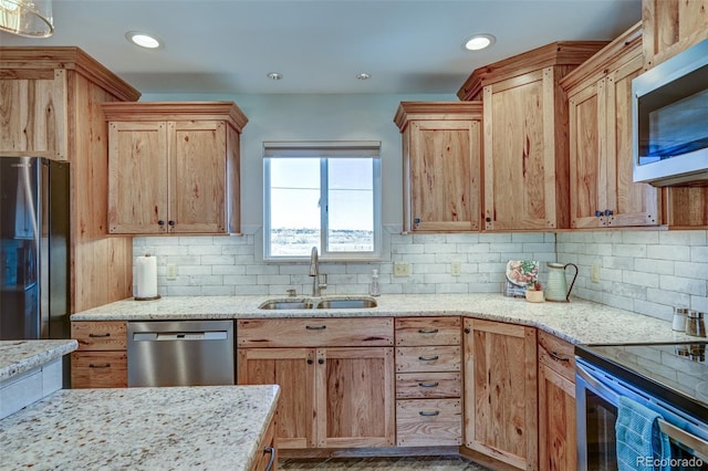 kitchen featuring stainless steel appliances, a sink, decorative backsplash, and light stone counters