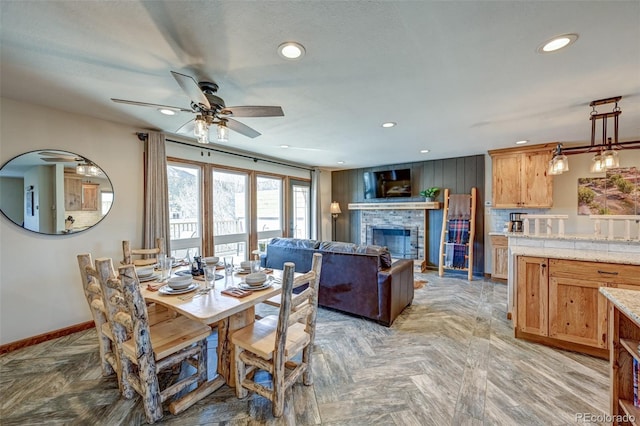 dining room with ceiling fan, a fireplace, baseboards, and recessed lighting