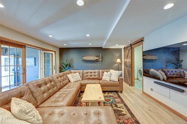 living room featuring light wood-type flooring, recessed lighting, washer / clothes dryer, and a barn door