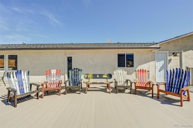 rear view of property featuring a shingled roof and stucco siding