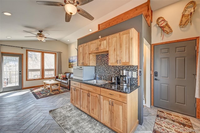 kitchen with tasteful backsplash, lofted ceiling, recessed lighting, light brown cabinetry, and a sink