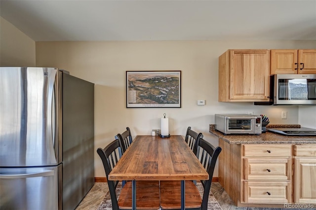 kitchen featuring stainless steel appliances, a toaster, and light brown cabinets