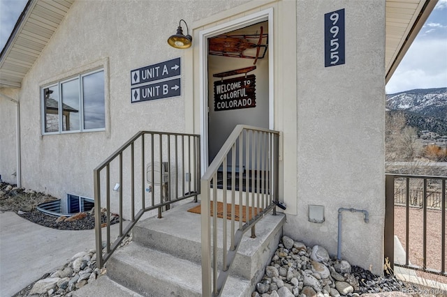 doorway to property featuring a mountain view, fence, and stucco siding