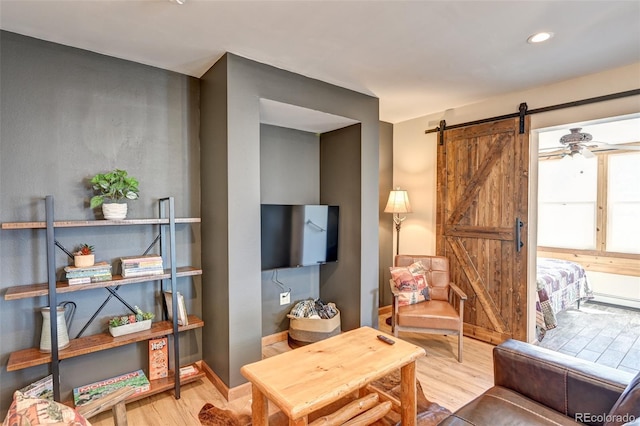 living room with a barn door, baseboards, wood finished floors, and recessed lighting