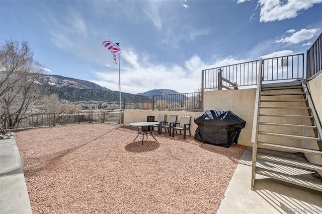 view of patio with a mountain view, fence, grilling area, and stairs