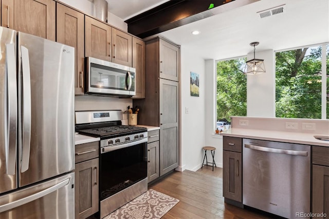 kitchen featuring stainless steel appliances, hanging light fixtures, and light hardwood / wood-style floors