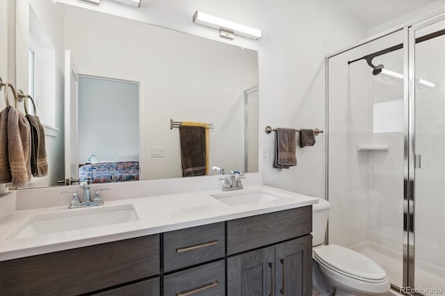 bathroom with toilet, dual bowl vanity, and a shower with shower door