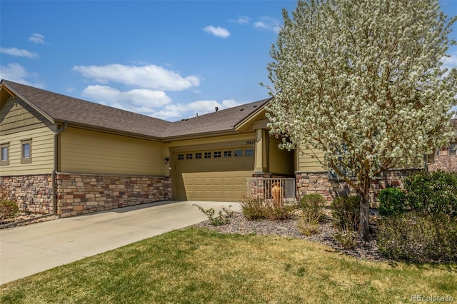 view of front facade featuring stone siding, concrete driveway, a garage, a front lawn, and roof with shingles