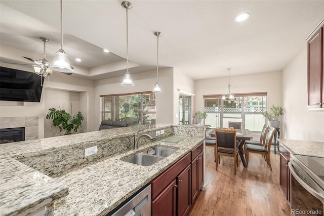 kitchen featuring a sink, open floor plan, light wood-style floors, a fireplace, and hanging light fixtures