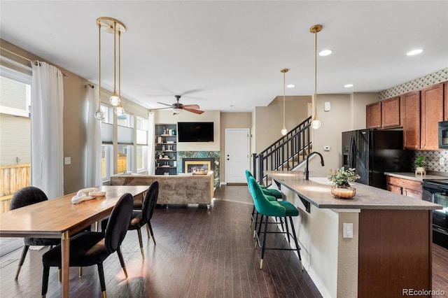 kitchen featuring ceiling fan, a high end fireplace, dark hardwood / wood-style flooring, and decorative light fixtures