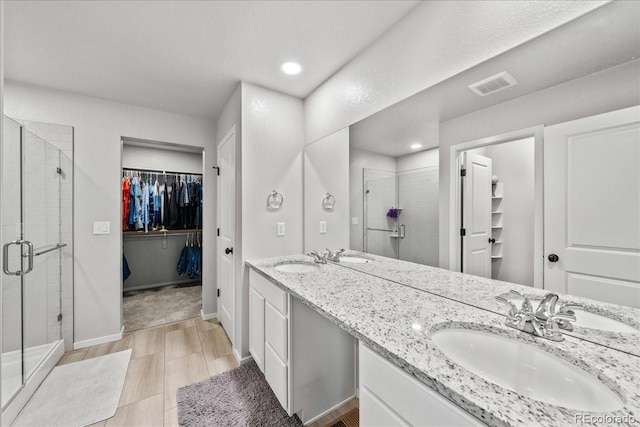 3674 Ronald Reagan Ave, Wellington, CO 80549 - bathroom featuring a shower stall, a spacious closet, double vanity, recessed lighting, and baseboards