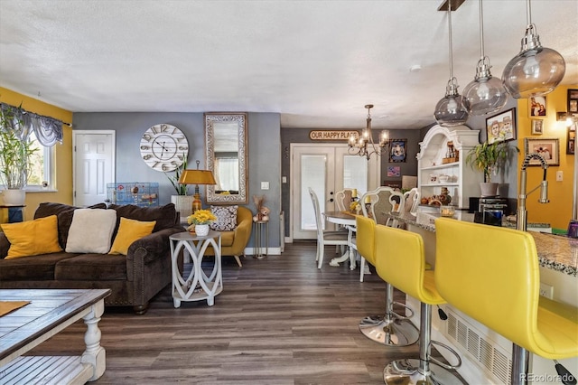 living room featuring dark wood-type flooring, a textured ceiling, a notable chandelier, and french doors