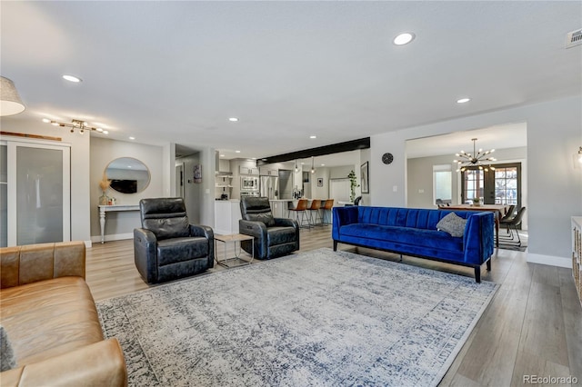 living room with an inviting chandelier and light wood-type flooring