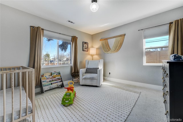 bedroom featuring light colored carpet, multiple windows, and a crib