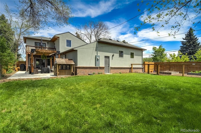back of property featuring stucco siding, a patio area, brick siding, a balcony, and a gate