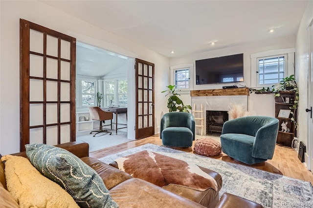 living room with a fireplace, vaulted ceiling, and light hardwood / wood-style flooring