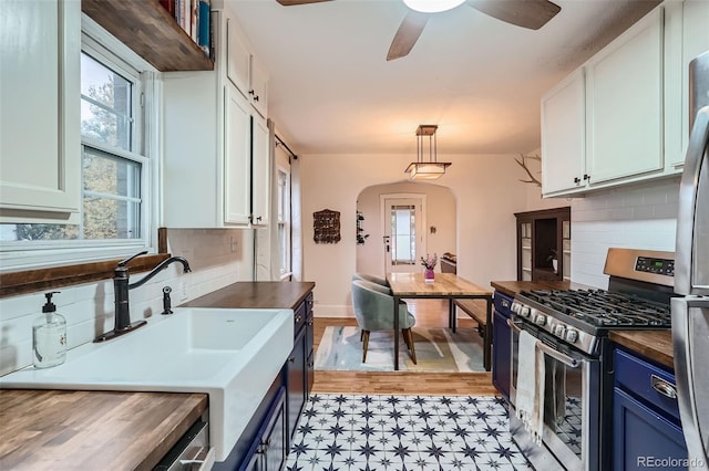 kitchen with tasteful backsplash, wooden counters, white cabinetry, appliances with stainless steel finishes, and hanging light fixtures