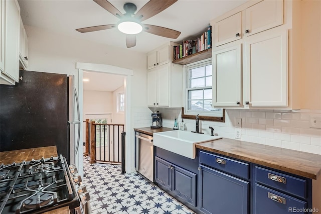 kitchen featuring butcher block counters, white cabinetry, blue cabinetry, and stainless steel appliances