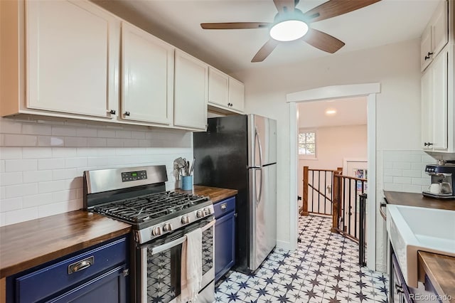 kitchen with butcher block counters, blue cabinetry, white cabinetry, and appliances with stainless steel finishes