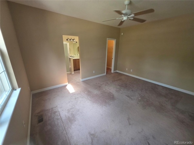 8911 Tappy Toorie Pl, Highlands Ranch, CO 80129 - unfurnished bedroom featuring a walk in closet, light colored carpet, ensuite bathroom, and ceiling fan