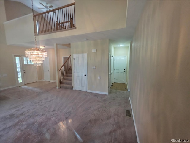 8911 Tappy Toorie Pl, Highlands Ranch, CO 80129 - unfurnished living room with carpet floors, a towering ceiling, stairs, a chandelier, and a ceiling fan