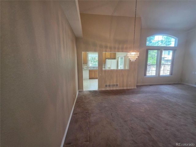 8911 Tappy Toorie Pl, Highlands Ranch, CO 80129 - unfurnished living room featuring a chandelier, dark carpet, and a towering ceiling