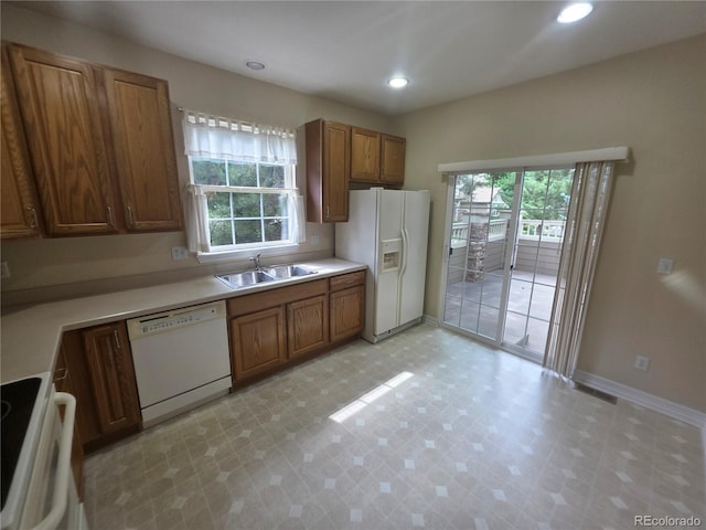 8911 Tappy Toorie Pl, Highlands Ranch, CO 80129 - kitchen featuring white appliances, plenty of natural light, brown cabinets, and recessed lighting