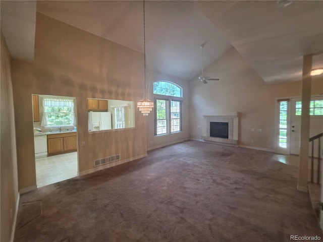 8911 Tappy Toorie Pl, Highlands Ranch, CO 80129 - unfurnished living room featuring high vaulted ceiling, carpet floors, a fireplace, and a ceiling fan