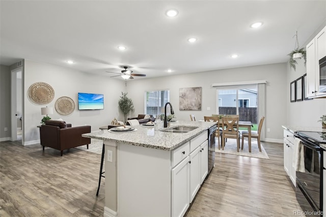 2328 Saddle Back Ct, Fort Lupton, CO 80621 - kitchen featuring a sink, black range with electric stovetop, a breakfast bar, recessed lighting, and light wood-type flooring