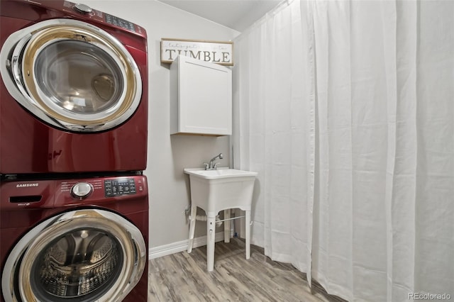2328 Saddle Back Ct, Fort Lupton, CO 80621 - washroom featuring stacked washing machine and dryer, wood finished floors, cabinet space, and baseboards