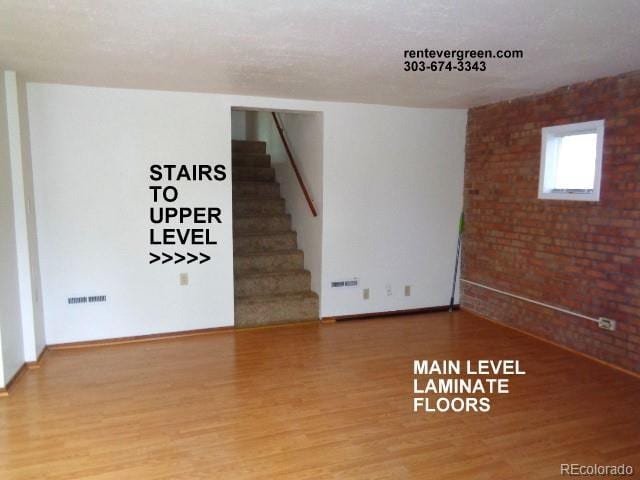 28127 Knowles Rd Unit A, B, & C, Evergreen, CO 80439 - unfurnished room featuring wood finished floors, brick wall, and stairway