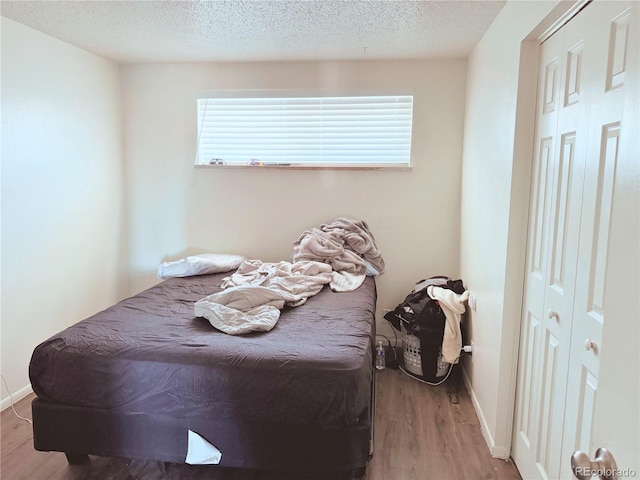 bedroom featuring light hardwood / wood-style floors and a textured ceiling