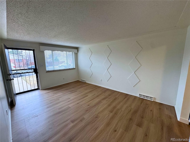 unfurnished room featuring visible vents, a textured ceiling, and wood finished floors