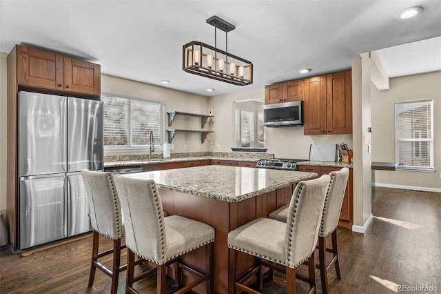 kitchen with sink, dark hardwood / wood-style flooring, decorative light fixtures, a kitchen island, and appliances with stainless steel finishes