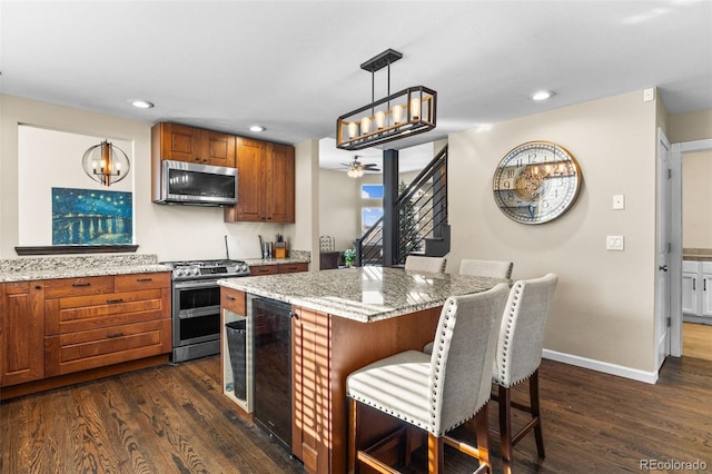 kitchen featuring appliances with stainless steel finishes, dark hardwood / wood-style floors, hanging light fixtures, and beverage cooler